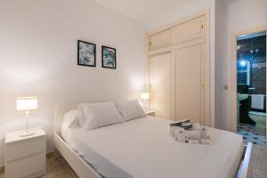 a white bedroom with a white bed and a lamp at El Bajondillo Beach a 30 metros de la playa in Torremolinos