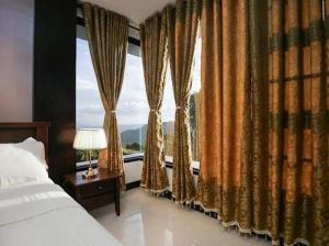 a bedroom with a bed and a large window at tagaytay transient ph in Tagaytay