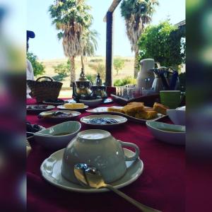 une table avec une théière sur un chiffon de table rouge dans l'établissement ferme Walila, à Douar Doukkara