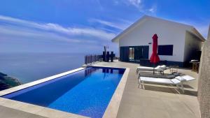 a house with a swimming pool next to the water at Villa Camacho xxvii in Arco da Calheta