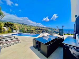 a patio with a table and chairs and a swimming pool at Villa Camacho xxvii in Arco da Calheta