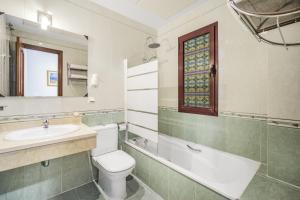 a bathroom with a toilet and a sink and a mirror at Don Juan Beach Resort in Estepona