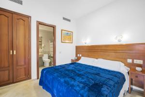 a bedroom with a bed with a wooden headboard and a bathroom at Don Juan Beach Resort in Estepona