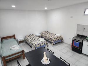 a room with two beds and a table and a stove at Monoambiente en el centro de la Ciudad. in Mercedes