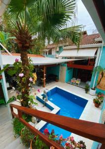uma piscina exterior com uma palmeira e uma casa em Tô na Praia Juquehy Pousada em Juquei
