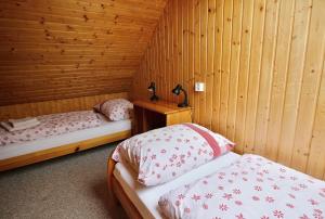 two beds in a room with wooden walls at Apartmány Jakub in Belá