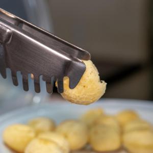 una persona sosteniendo un pedazo de comida en un cuchillo en Pousada Bellissima Italia, en Luís Correia