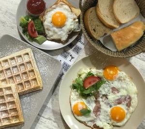 tres platos de comida con huevos, pan y tostadas en Monarchia Apartman Sunny en Mosonmagyaróvár