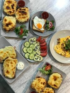 a table topped with plates of food with eggs and vegetables at Monarchia Apartman Sunny in Mosonmagyaróvár