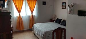 1 dormitorio con 1 cama y una ventana con cortinas de color naranja en Ayres Serranos en Merlo