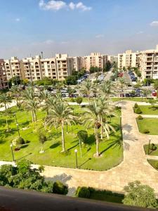 un parque con palmeras frente a un gran edificio en Luxurious 3 BR Rustic Apartment Overlooking Huge Garden - For Families and Couples en El Cairo