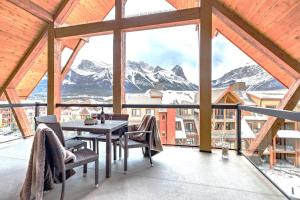 einen Balkon mit einem Tisch, Stühlen und Bergen in der Unterkunft LUXE Penthouse with Mountain Views Solar A Resort & Spa in Canmore