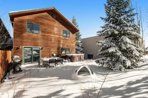 a log cabin with a table and a tree in the snow at Twenty Grand Chalet in Silverthorne