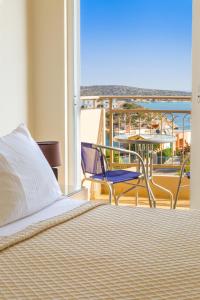 Crete View في ماراثي: غرفة نوم مع سرير وبلكونة مع طاولة وكراسي