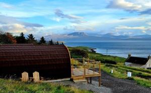 a large wooden building with a view of the ocean at The Sleepy Crofter Glamping - Achiltibuie in Achiltibuie