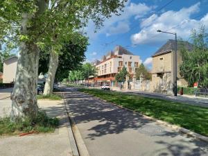 uma rua vazia com uma árvore e edifícios em Bel Appartement Grande Terrasse avec parking à Dijon em Dijon