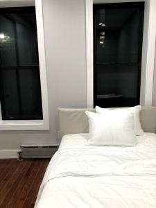 een wit bed met 2 kussens en 2 ramen bij Cozy cottage in Bronx with good bedrooms in West Farms