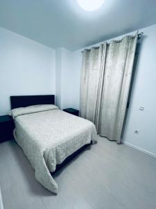 a white bedroom with a bed and a window at Apartamento Coman Av Rey Juan Carlos I in Torrent