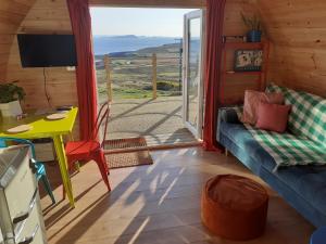 a living room with a couch and a table and a window at The Sleepy Crofter Glamping - Achiltibuie in Achiltibuie