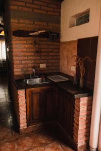 een keuken met een wastafel en een bakstenen muur bij La Casita de Salta in Salta