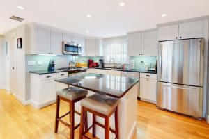 a kitchen with white cabinets and a stainless steel refrigerator at Chic Spacious Home Half a Mile From Commercial Street in Provincetown
