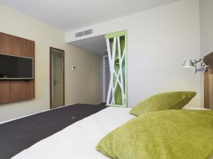 a bedroom with a bed with green pillows and a tv at Campanile Bordeaux Ouest - Mérignac Aéroport in Mérignac +35 photos