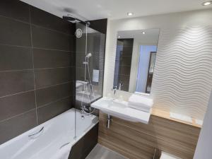 a bathroom with a tub and a sink and a mirror at Campanile Bordeaux Ouest - Mérignac Aéroport in Mérignac