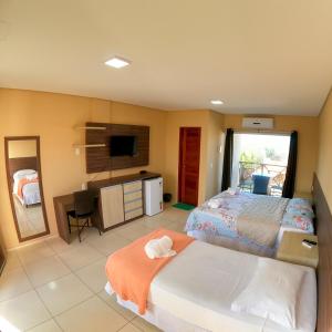 Schlafzimmer mit einem Bett, einem Schreibtisch und einem TV in der Unterkunft Pousada Bellissima Italia in Luis Correia