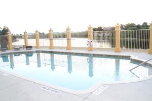 a swimming pool with blue water in front of a fence at La Quinta by Wyndham Bonita Springs Naples North in Bonita Springs