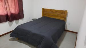 a bed with a black comforter in a room at A Casa do Júnior em Visconde de Mauá in Visconde De Maua