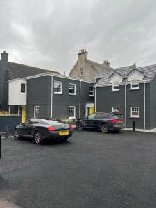 two cars parked in a parking lot in front of buildings at The Seelies - Luxury Aparthotel - By The House of Danu in Kingussie