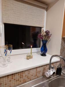 a kitchen counter with a window with a candle and a sink at Namelis uždarame kieme in Šiauliai