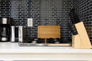 um balcão de cozinha com um fogão e uma parede de tijolos pretos em 69-2A PRIME Lower East Side 1br Apt Brand New em Nova York