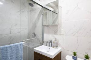 uma casa de banho branca com um lavatório e um chuveiro em 69-2A PRIME Lower East Side 1br Apt Brand New em Nova York