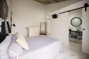 a white bedroom with a bed and a mirror at Casa suig in Baena