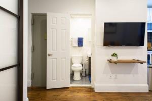a bathroom with a toilet and a television on a wall at 69-2B Prime Lower East East BRAND NEW 1br Apt in New York