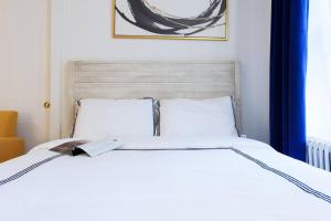 a white bed with a book on top of it at 24-17 Renovated Studio Prime Location WD in New York