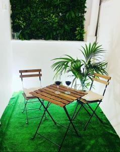 a wooden table with two wine glasses and two chairs at Stadiumapartament in Santa Cruz de Tenerife