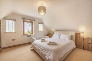 Un dormitorio con una gran cama blanca y una ventana en Rainbow Barns, en Bourton on the Water