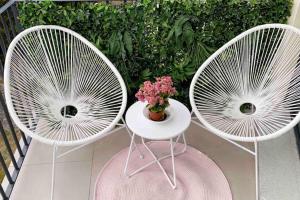 twee witte stoelen en een tafel met bloemen op een balkon bij CLICHY SOUS BOIS APPARTEMENT RÉCENT & CHALEUREUX in Clichy-sous-Bois