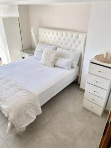 uma cama branca com almofadas e uma cómoda num quarto em CLICHY SOUS BOIS APPARTEMENT RÉCENT & CHALEUREUX em Clichy-sous-Bois