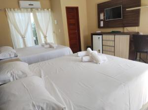 2 camas en una habitación de hotel con sábanas blancas en Pousada Bellissima Italia, en Luís Correia