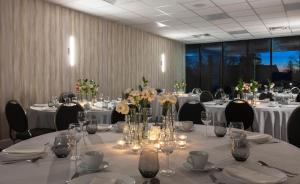 een vergaderzaal met tafels en stoelen met bloemen en kaarsen bij Strata Hotel in Kingston