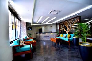 a lobby with blue couches and a plant in a room at Victoria Mews Hotel in Kampala