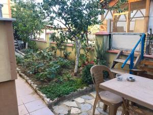 eine Terrasse mit einem Tisch und Stühlen sowie einem Garten in der Unterkunft Altınkum Sahil'de bahçeli nezih yazlık in Edremit