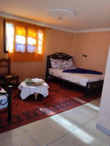 Un dormitorio con una cama y una mesa sobre una alfombra en maison familiale chez Salwa, en Ouarzazate