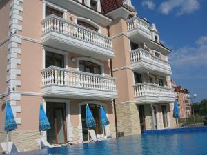 a large building with chairs and umbrellas next to a swimming pool at Guest House Aristokrat in Obzor