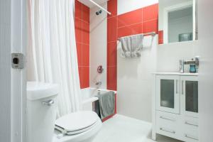 La salle de bains est pourvue de toilettes blanches et d'un mur rouge. dans l'établissement 24-9 New Prime Gramercy Subway W D in unit, à New York