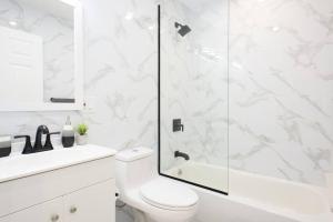 a white bathroom with a shower and a toilet at 240-5 NEW Prime Location STUDIO W&D in unit in New York