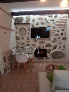 SEÑORÍO DE ORGAZ II في طليطلة: غرفة معيشة مع طاولة وتلفزيون على جدار حجري